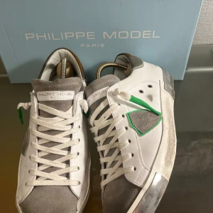 Vita Philippe Model prsx - Snygga vita prsx modell från Philippe Model  med gråa detaljer och gröna accenter. Andvända ett fåtal gånger. Skorna har en klassisk snörning och en stilren design. Perfekta för en trendig look. Pris kan diskuteras vid snabb affär. Byten kan även vara intressant i storlek 42