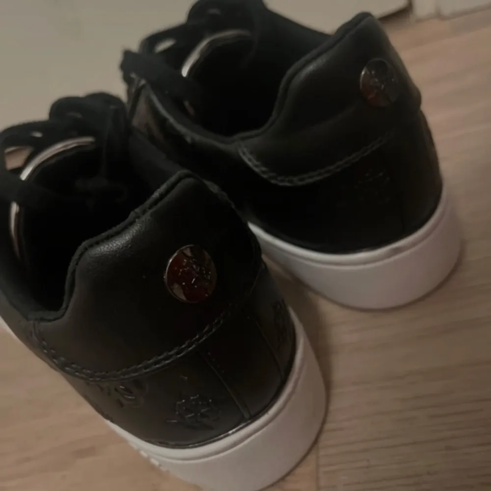 Helt nya svarta sneakers från Guess med diskret mönster och vita sulor. Skorna har snörning och metalliska detaljer vid snörhålen. Perfekta för en stilren look. Aldrig använda endast tesdad! . Kengät.