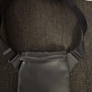 Svart axelväska från Boss - Säljes: Hugo Boss väska i läder, stilren design med praktiska fack. Tidlös och i mycket gott skick.