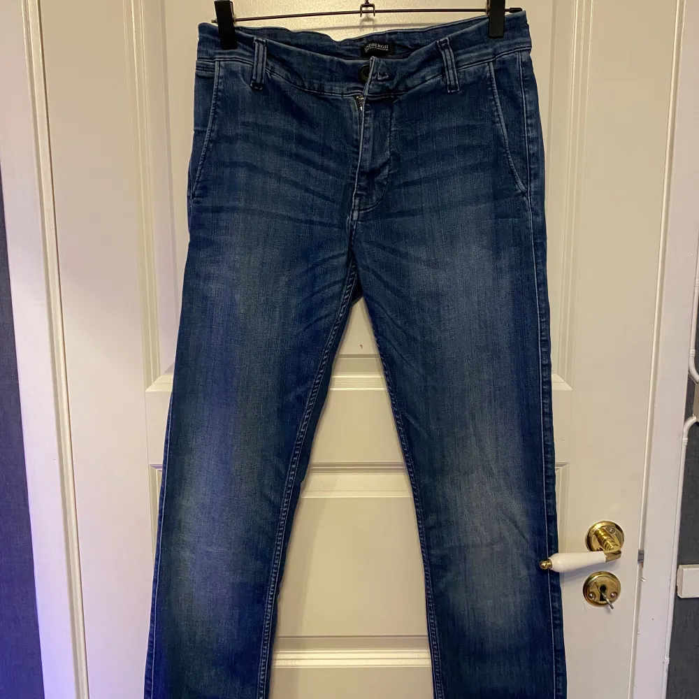 Snygga blå jeansbyxor från Lindbergh med klassisk design. Byxorna har en rak passform och är utrustade med knappar och dragkedja. Perfekta för en stilren look.. Farkut & Housut.