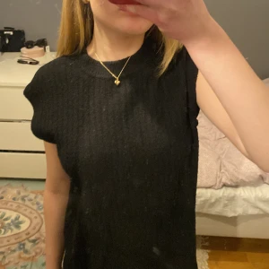 Svart ärmlös topp från Neo Noir - Snygg svart ärmlös topp från Neo Noir. Perfekt för en stilren look med sin ribbade design. Passar bra till både jeans och kjol. Ett måste i garderoben för den som gillar enkelhet med stil.