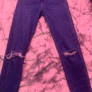 Blå jeans från Never Denim - Snygga blå jeans från Never Denim med slitna detaljer på knäna och fransiga benslut, tillverkade i en bomullsblandning för extra komfort. 🫶