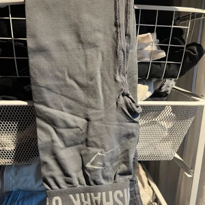 Grå träningsbyxor från Gymshark - Snygga grå träningsbyxor från Gymshark med logga på benet. Perfekta för gymmet eller löprundan. De har en tight passform och är tillverkade i ett stretchigt material för maximal rörelsefrihet.