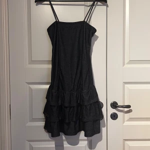 Mörkblå klänning med volanger - Snygg jeansfärgad klänning med smala axelband och flera lager volanger💘