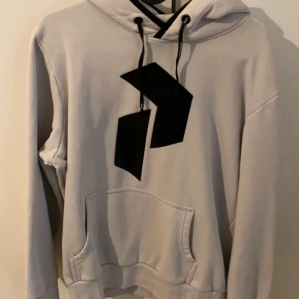 Säljer en snygg beige hoodie från Peak Performance i storlek S. Den har en stor svart grafisk design på framsidan och en praktisk magficka. Perfekt för höst och vinter med sin mysiga huva och långa ärmar. Passar både till vardags och chillkvällar. 🖤. Hoodies.