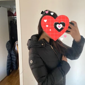 Svart pufferjacka med dragkedja - Säljer en snygg svart hollies jacka  i storlek 36. Jackan har en dragkedja framtill och är perfekt för kyliga dagar. Den är långärmad och har en mysig huva. Perfekt för höst och vinter!