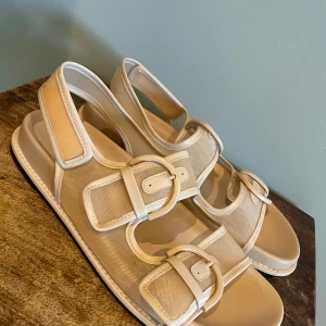 Beige sandaler med spänne - Snygga beige sandaler med stora spännen, stilren design med justerbara remmar för perfekt passform. Perfekta för sommardagar och ger en avslappnad men chic look, även schyssta inomhus. Använda EN kväll. Därför som nya. Inköpta på ZARA för 699 kr.