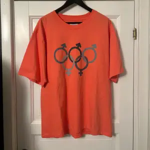 Säljer en cool orange/rosa t-shirt från ERL med OS loggan. Tröjan är kortärmad och har en oversized passform. Tjockt och lyxigt material. Den är mer rosa i verkligheten men svårt att få på bild! Strl M men passar L. Skicka gärna frågor eller offers!