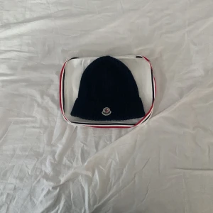 Moncler mössa - Den har mått 65 cm i omkrets och har blivit använd ett par gånger under vintern, villig att byta eller sänka priset, säljer den för att den inte riktigt är min stil längre 