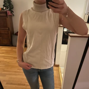 Beige ärmlös polotröja - Beige polotröja med hög krage. Knappt använd