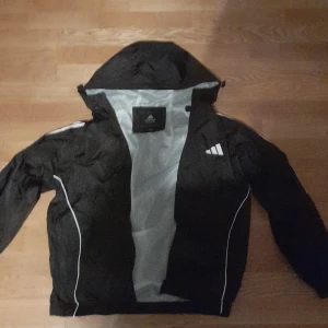 Svart vindjacka från Adidas - OPS inte ÄKTA❗ fungerar perfekt för fotbollsträningen eller en joggingrunda vid kallare väder. Har bara använt den en gång. Passar dig mellan 160-170cm