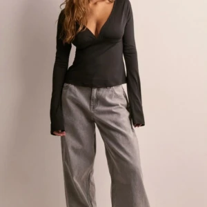 Svart långärmad topp med v-ringning - Snygg svart långärmad topp med v-ringning och en elegant rosett i ryggen. Säljer då den var för liten. Aldrig använd! Prislappen är kvar