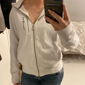 Vit huvtröja från Sail Racing - Snygg vit huvtröja från Sail Racing med dragkedja och broderad logga på bröstet. Super fin och såå skön! Köpte för 1500 och säljer för endast 900!