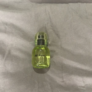H&M Pear Parfym - Oanvänd fräsch och fruktig parfym från H&M med en tydlig pärondoft. Flaskan är liten och kompakt med en ljusgrön färg som matchar doften. Perfekt för att bära med sig i väskan för en snabb uppfräschning under dagen.