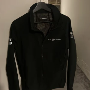 Svart jacka från Sail Racing S - Säljer nu denna sjukt Snygga svart jacka från Sail Racing med dragkedja och logotyp på bröstet och ärmen, som passar riktigt bra vid regnigt väder, skick 9/10 använd men ser ut som ny, priser går ashälvklart att diskutera!!