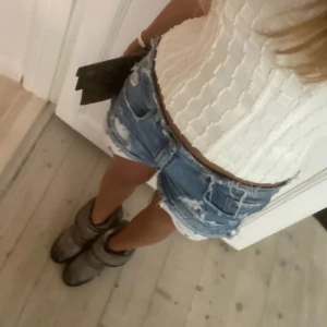 Blå jeansshorts med slitningar - Säljer ett par snygga blå jeansshorts med slitningar och fransiga kanter. Passar så bra till sommaren!🌺💞🏝️