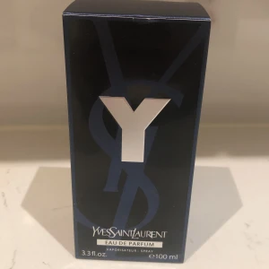 Yves Saint Laurent Y Eau de Parfum - Yves Saint Laurent Y Eau de Parfum i en elegant svart förpackning med en stor silverfärgad bokstav Y på framsidan. Flaskan innehåller 100 ml av denna ikoniska doft, perfekt för den moderna mannen.
