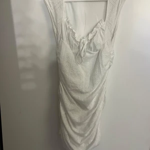 Vit klänning från SHEIN - Säljer en söt vit klänning från SHEIN med volangdetaljer och knytning framtill. .