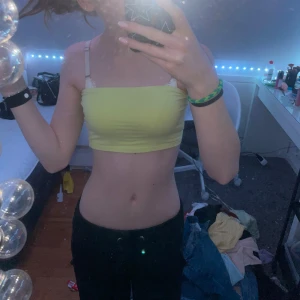 Gul tubtopp från Gina Tricot - Säljer en snygg gul tubtopp från Gina Tricot. Perfekt för varma sommardagar. Toppen är enkel och stilren, vilket gör den lätt att matcha med olika outfits. Passar perfekt för en avslappnad look.