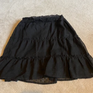 Svart kjol från New Yorker  - Snygg svart kjol från New Yorker i storlek XS. Kjolen har ett prickigt mönster och volangdetaljer som ger en fin rörelse. Perfekt för att lägga till en touch av stil till din outfit 💞