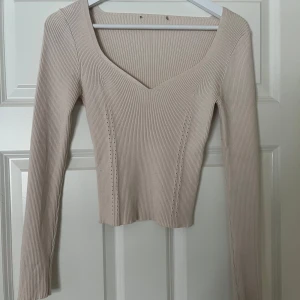 Beige ribbad tröja - Säljer en stilren beige ribbad tröja med v-ringning. Tröjan har långa ärmar och lite figursydd passform. Perfekt för både vardag och speciella tillfällen.💗💖