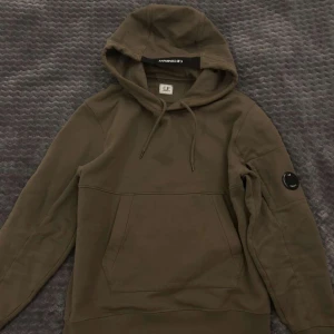 Olivgrön hoodie från C.P. Company - Snygg olivgrön hoodie från C.P. Company. Använt den en eller två gånger så är nyskick. Köpt för 2800.
