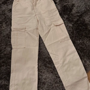 Beige cargopants - Snygga beige cargopants med flera praktiska fickor på sidorna. Perfekta för en avslappnad stil och passar till många olika outfits. Byxorna har en rak passform och är tillverkade i ett bekvämt material.