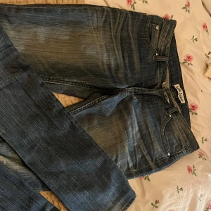 Blå jeans från Acne  - Säljer ett par klassiska blå jeans från Acne Studios med en snygg tvätt. De har en rak passform och är perfekta för en avslappnad stil. stängs med dragkedja och knapp.