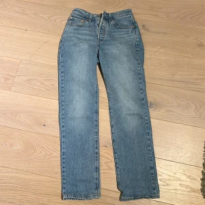 Levis 501 jeans  - Klassiska Levis 501 jeans i blå denim med rak passform. De har en traditionell femficksdesign och knappgylf. Perfekta för en avslappnad stil.