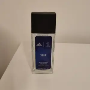 Säljer en Adidas Star Fresh Fragrance, en deo natural spray med en fräsch doft. Flaskan är genomskinlig med en blå etikett och svart lock. Innehåller 75 ml.