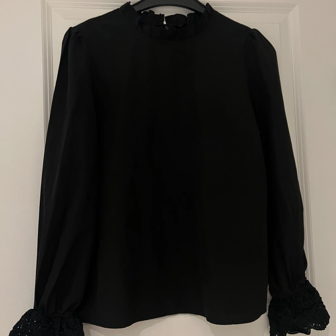 Svart blus med blommig design på armen