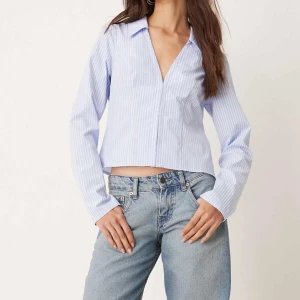 Blå och vit randig figursydd skjorta - Snygg ljusblå figursydd skjorta med diskreta ränder och en djup v-ringning. Blusen har långa ärmar och en stilren design som passar perfekt för både vardag och fest. Skulle säga storlek 38-40. Den är helt ny och säljer pga den var för liten för mig men missade retur datumet🫣Köpt för 429kr Skriv privat om du undrar något eller för fler bilder. Kan skickas eller mötas upp i Linköping. Finns på fler sidor.