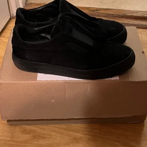 Svarta Axel Arigato laceless - Snygga svarta sneakers från Axel Arigato i mocka. De har en stilren design utan snörning och en robust sula. Perfekta för en minimalistisk look. Skicka 8/10 men smutsiga därav lågt pris. 