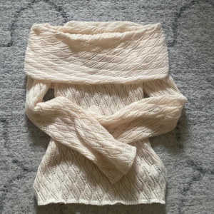 Beige stickad offshoulder-tröja - Säljer en snygg beige stickad offshoulder-tröja med ett fint mönster. Tröjan har långa ärmar och en lös passform, perfekt för en stilren look. Passar bra till både kjol och byxor.