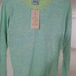 Grön långärmad tröja från Circa - Snygg och bekväm grön långärmad tröja från Circa. Perfekt för en avslappnad stil med en subtil melerad effekt. Tröjan har en v-ringad hals och är tillverkad i ett mjukt material.