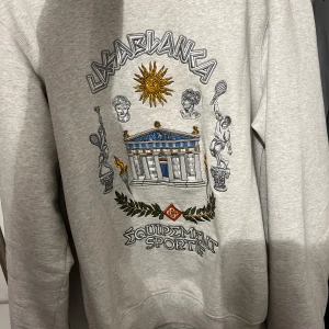 Grå sweatshirt från Casablanca - Säljer en grå sweatshirt från Casablanca med ett detaljerat tryck på framsidan. Tröjan har långa ärmar och en avslappnad passform. Perfekt för en stilren och bekväm look. Inga skador kvitto finns från nk. ( nypris 5500