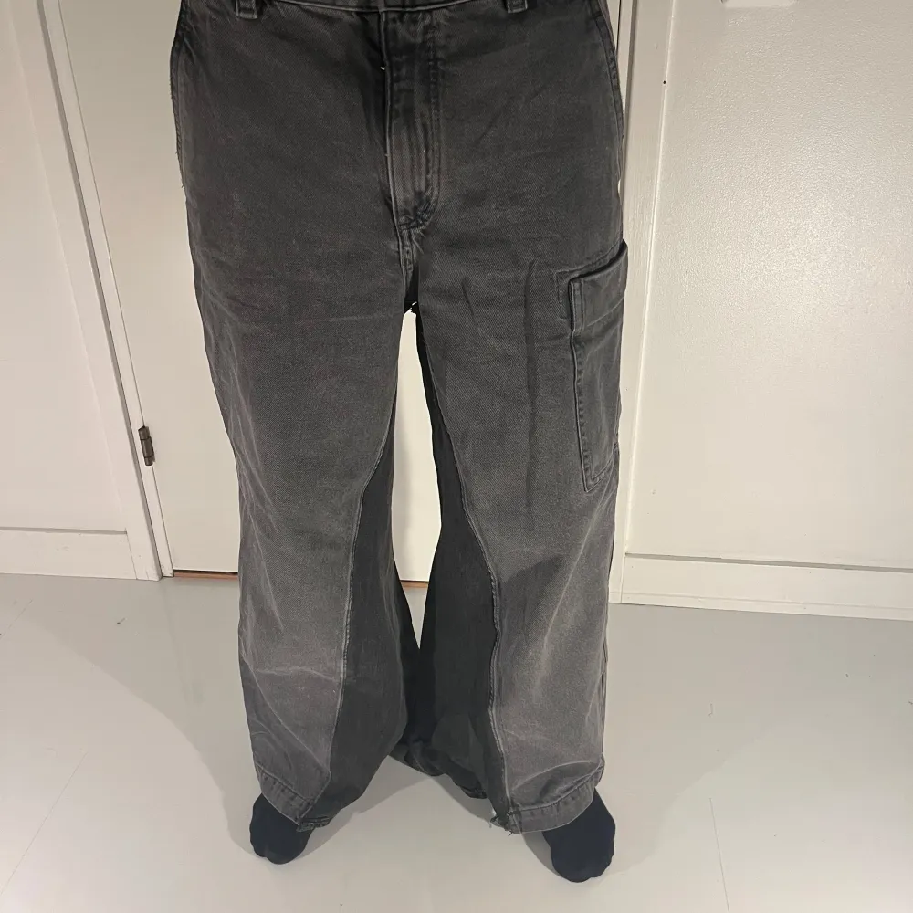 Snygga grå cargobyxor från COS med en loose passform. Byxorna har en praktisk ficka på sidan och är perfekta för en avslappnad stil. Tillverkade i ett slitstarkt material som ger en cool look.. Farkut & Housut.