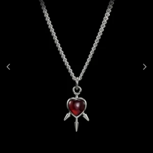 Maria Nilsdotter halsband - Elegant halsband med en röd hjärtformad berlock i silverfärgad kedja. Berlocken har en pilformad detalj som ger en unik touch. Perfekt till din outfit. Köpte bara ett par månader sen och så fint! Modellen heter three of sword