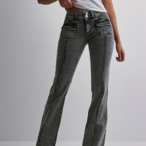 Grå jeans med fickdetaljer - Snygga grå jeans från Nelly med låg midja och bootcut-stil. De har fickdetaljer framtill och dubbla knappar i midjan. Sitter super fint! Använda fåtal gånger därav priset, kan däremot dirkuteras💕