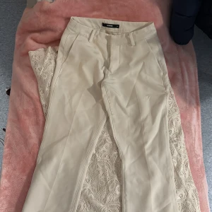 Vita lågmidjade kostymbyxor från Bik Bok - Snygga beige kostymbyxor från Bik Bok i storlek 34. Byxorna har en klassisk design med en slitt och diskreta fickor baktill. 