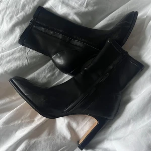 Svarta boots med klack  - Svarta boots med klack, enbart använda en gång då de var för små. Strl 39. Vet ej material, skinn imitation. Lite slitna på insidan (se bild). Från NAKD, nypris ca 800 kr. Mitt pris: 180 kr.