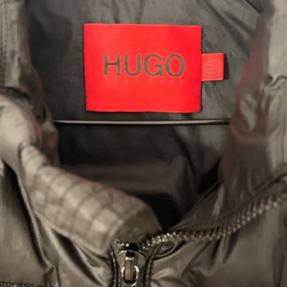 Snygg svart dunväst från Hugo med dragkedja och hög krage. 7/10 i skick och pris kan diskuteras!. Takit.