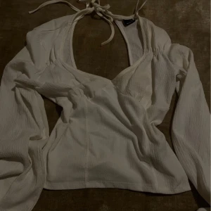 Vit blus med knytband - Säljer en stilren vit blus med knytband i halsen. Blusen har långa ärmar och en lätt ribbad struktur som ger en elegant touch. Perfekt för både vardag och speciella tillfällen.🤍
