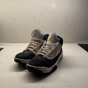 Nike Air Jordans i svart och vit - Snygga Nike Air Jordans i svart och vit med gröna detaljer. Skorna har en klassisk snörning och den ikoniska Jumpman-loggan i guld på plösen. Perfekta för dig som vill ha en stilren och sportig look.