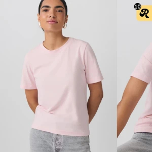 Ljusrosa t-shirt - Säljer en ljusrosa t-shirt i bomull. Den har en klassisk rund hals och korta ärmar, perfekt för en avslappnad stil. Passar bra till jeans eller kjol för en enkel och snygg look.