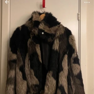 Mönstrad pälsjacka från BikBok - Säljer en supercool pälsjacka från BikBok i storlek M. Den har ett djärvt mönster i svart och beige som verkligen sticker ut. Perfekt för att hålla sig varm och snygg under hösten och vintern. Jackan har långa ärmar och stängs med knappar framtill. Ett måste för garderoben!