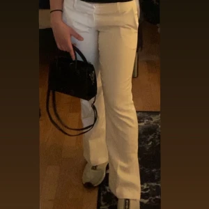 Vita byxor med bootcut - Säljer ett par snygga vita kostym  byxor med bootcut-stil. De är perfekta för både vardag och fest. Byxorna har en låg midja och en stilren design som passar till det mesta. Perfekta för vår och sommar! Använda två gånger . Från bik bok 