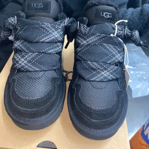 Svarta sneakers från UGG - Säljer ett par svarta UGG Lomel Black. Skorna är helt nya och oanvända. Kvitto, box, extra snören och alla andra tillbehör finns. Skorna är i storlek 37. Priset kan diskuteras.