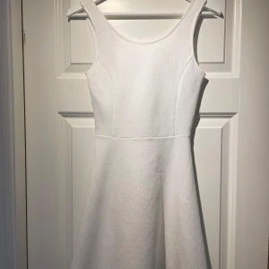 Vit klänning från H&M Divided - Säljer en stilren vit klänning från H&M Divided. Klänningen har en rund halsringning och har en enkel, elegant design. 
