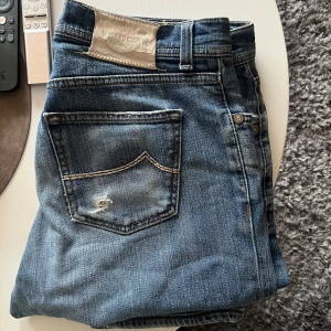 Blå jeans från Jacob Cohen - Säljer ett par snygga blå jeans från Jacob Cohen. De har en klassisk femficksdesign med knappar och en bekväm passform. Perfekta för en avslappnad stil. Nypris ca 7000kr mitt pris 999kr🤝 byten kan även också vara intressant!!!
